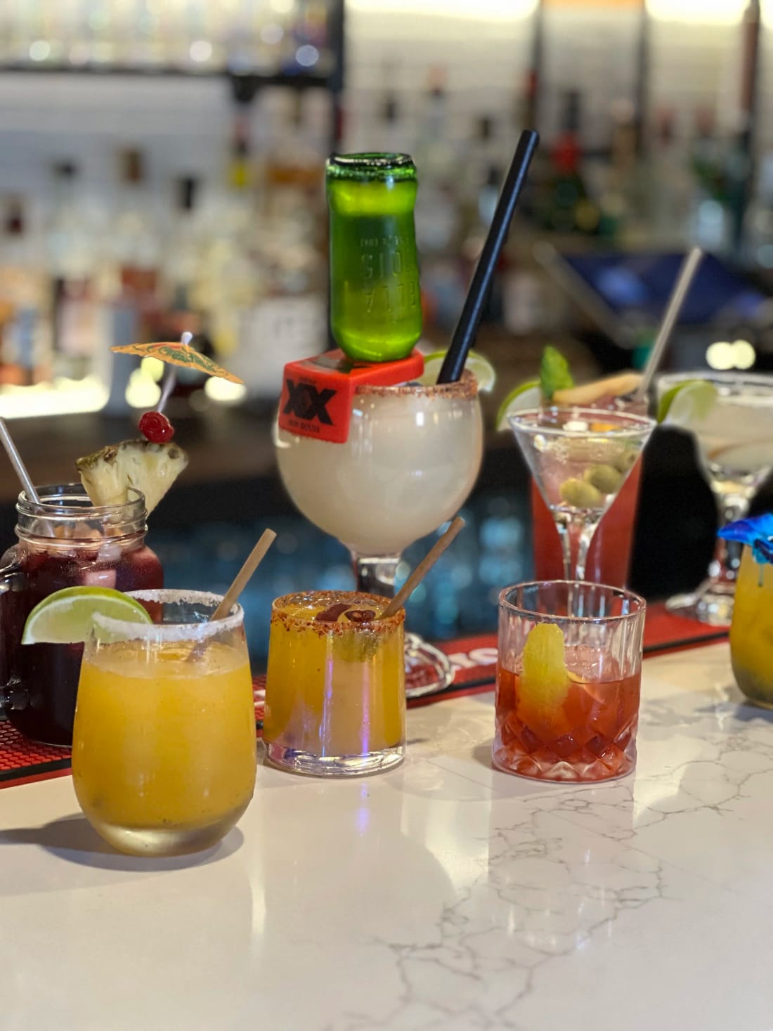 Cocktails on the bar with a chili-rimmed glass in the foreground