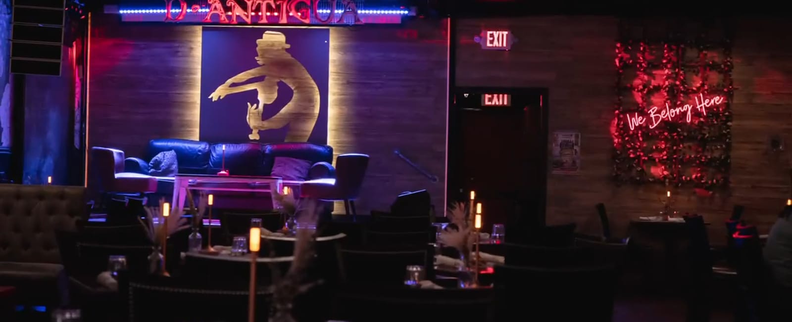 Inside the D'Antigua lounge at night, with tables, candles and the neon sign